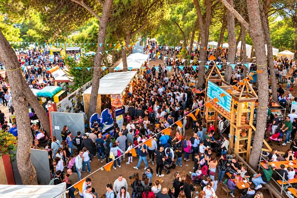 La folla fra i pini nell’area food, fra stand, bandierine e tavolate — Parco d’Autunno di Gallipoli
