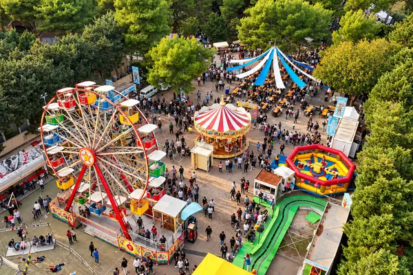 Il luna park dall’alto: ruota panoramica, giostra a cavalli e scivolo gonfiabile fra i pini — Parco d’Autunno di Gallipoli