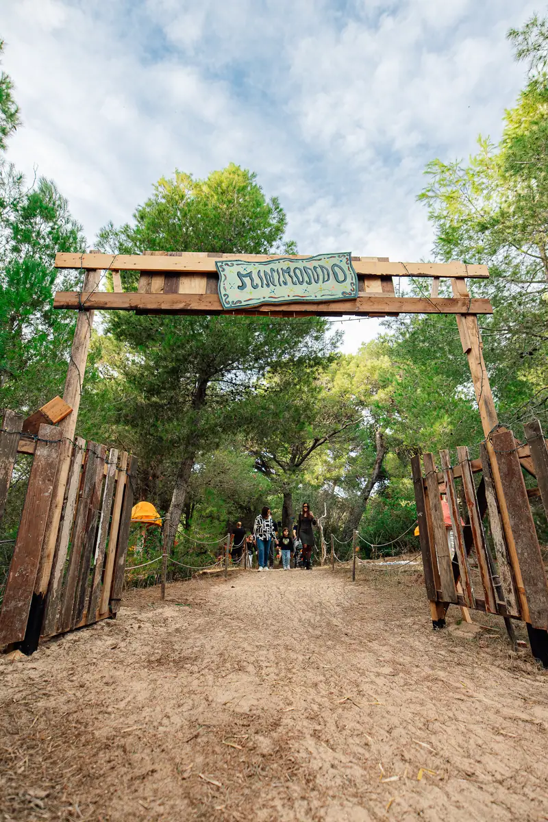 Visitatori sotto il portale di legno del Minimondo, tra i pini — Parco d’Autunno al Raffo Parco Gondar di Gallipoli