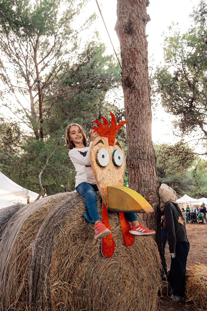 Bambina seduta sul fieno accanto a un gallo di legno — Parco d’Autunno al Raffo Parco Gondar di Gallipoli