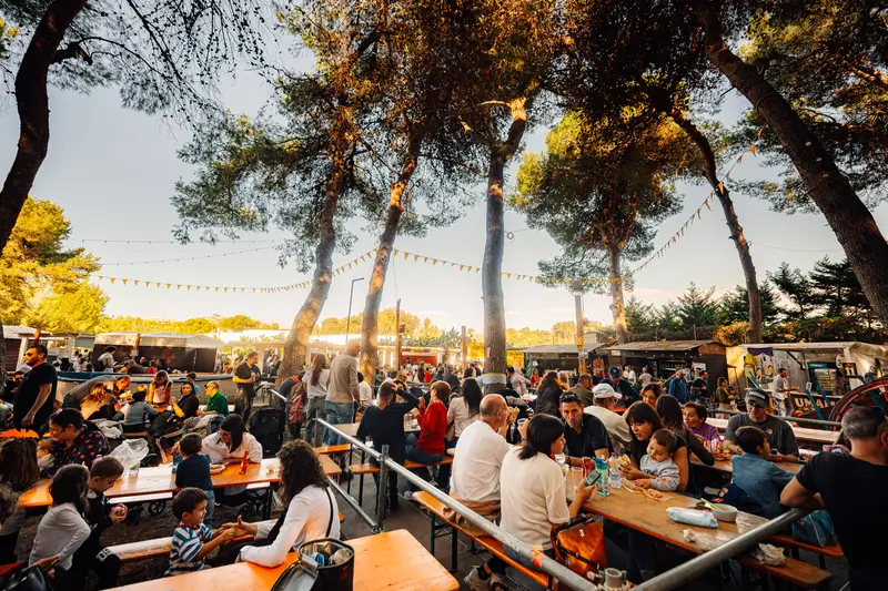 Le lunghe tavolate dell’Oktoberfest piene di gente, sotto i pini — Parco d’Autunno 2026 al Raffo Parco Gondar di Gallipoli