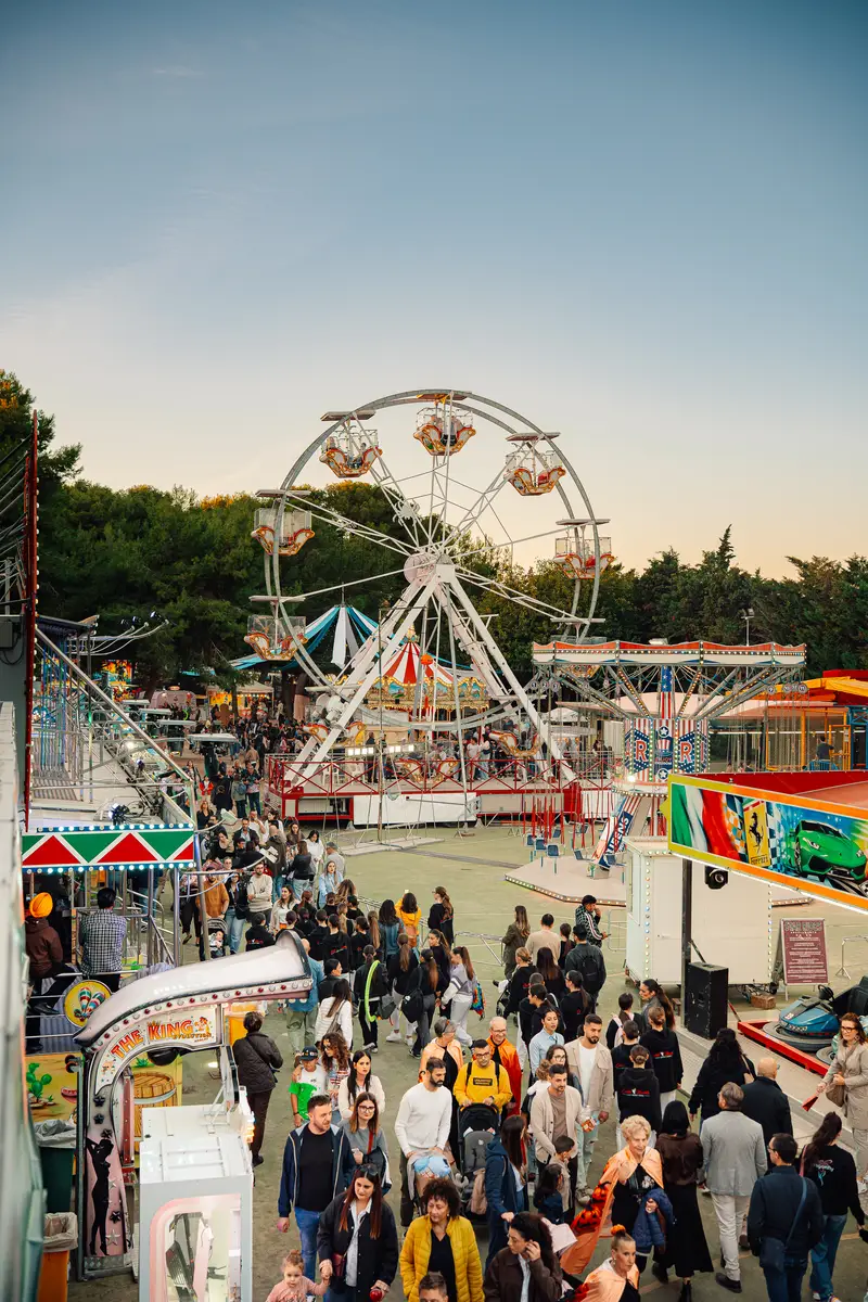 Il piazzale del luna park con la ruota panoramica e la folla fra le attrazioni — Parco d’Autunno 2026 al Raffo Parco Gondar di Gallipoli