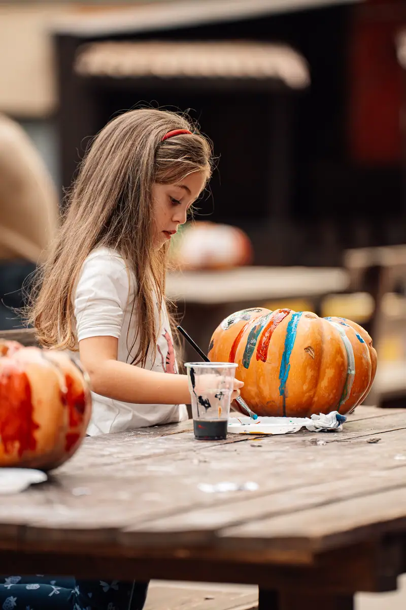 Bimba dipinge zucca al tavolo
