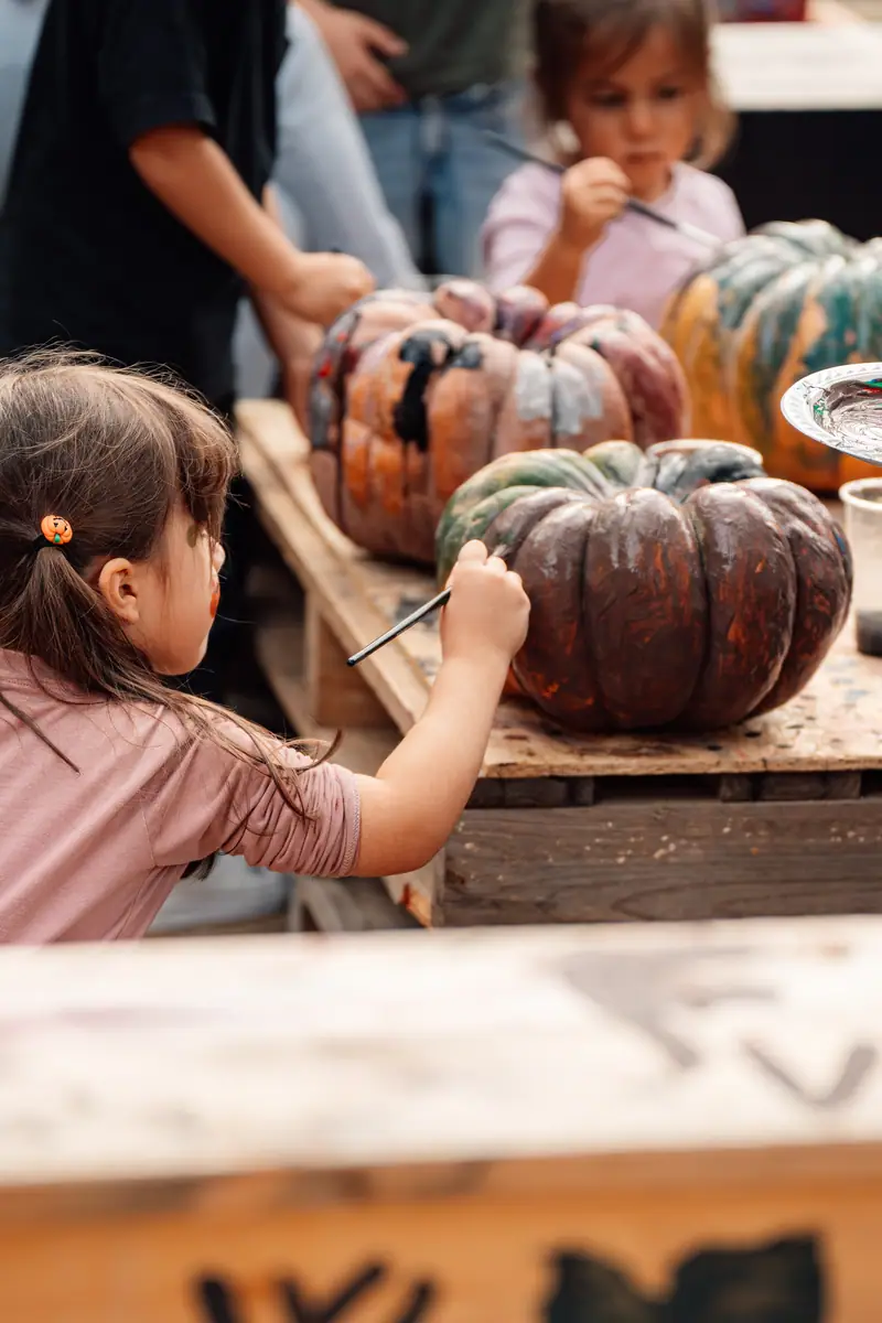 Bimba dipinge zucca al tavolo